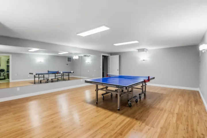 Expansive room featuring wood-finish flooring, full-wall mirrors, and modern flush-mount lighting
