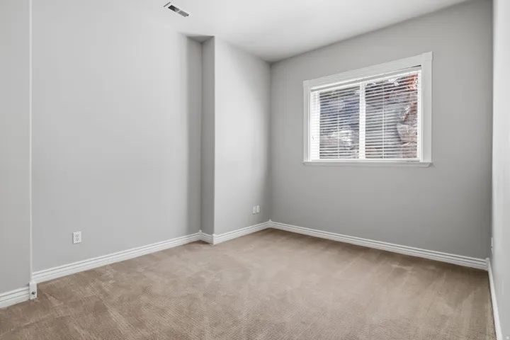 Neutral-toned carpeting, light gray wall finishes, white trim, and a window with blinds