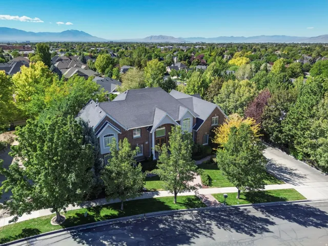 Brick exterior, multi-gabled roof, mature landscaping, paved driveway, and mountain backdrop