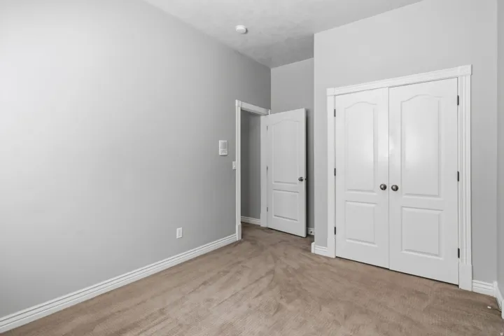 Neutral wall paint, plush carpet flooring, white trim, and white paneled doors