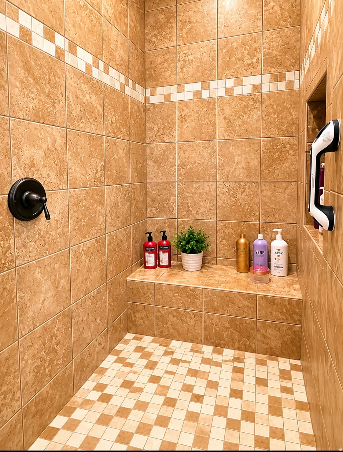 Tiled shower enclosure featuring a bronze-finish control knob, an integrated shower bench, a recessed wall niche, and a checkered mosaic tile floor