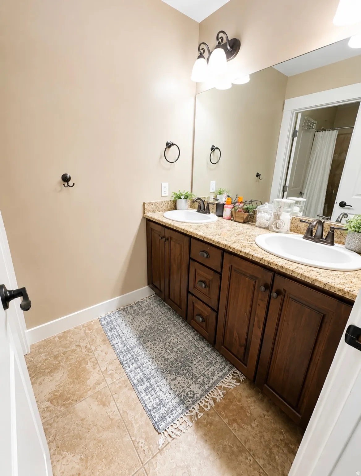 Double vanity with built-in cabinetry, dual white undermount sinks, and granite-look countertops