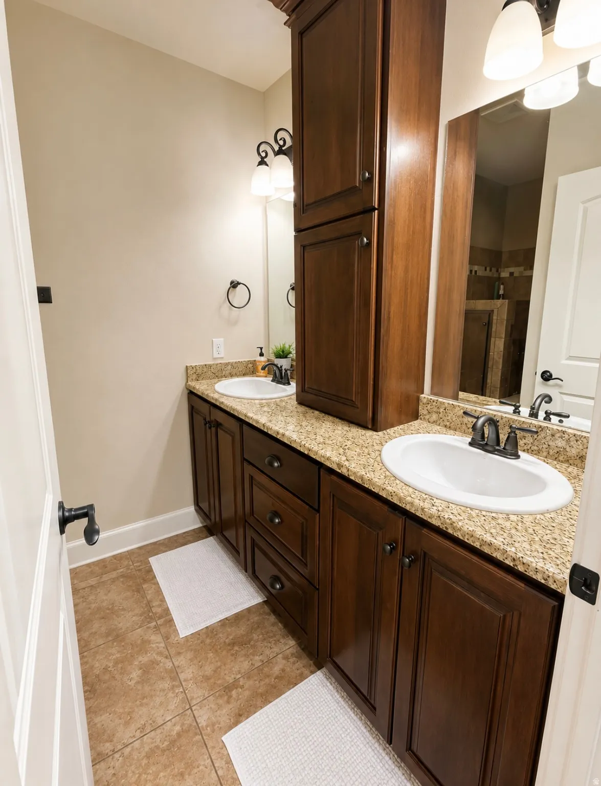 Dual vanity featuring granite countertops, undermount sinks, and dark wood cabinetry