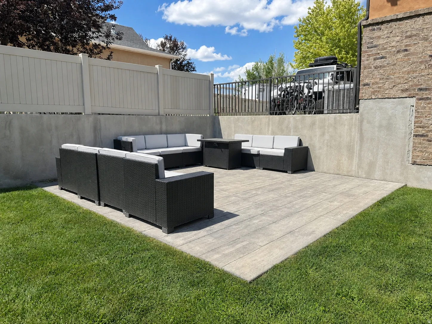 Expansive outdoor patio with concrete pavers, surrounded by a manicured lawn and privacy fencing