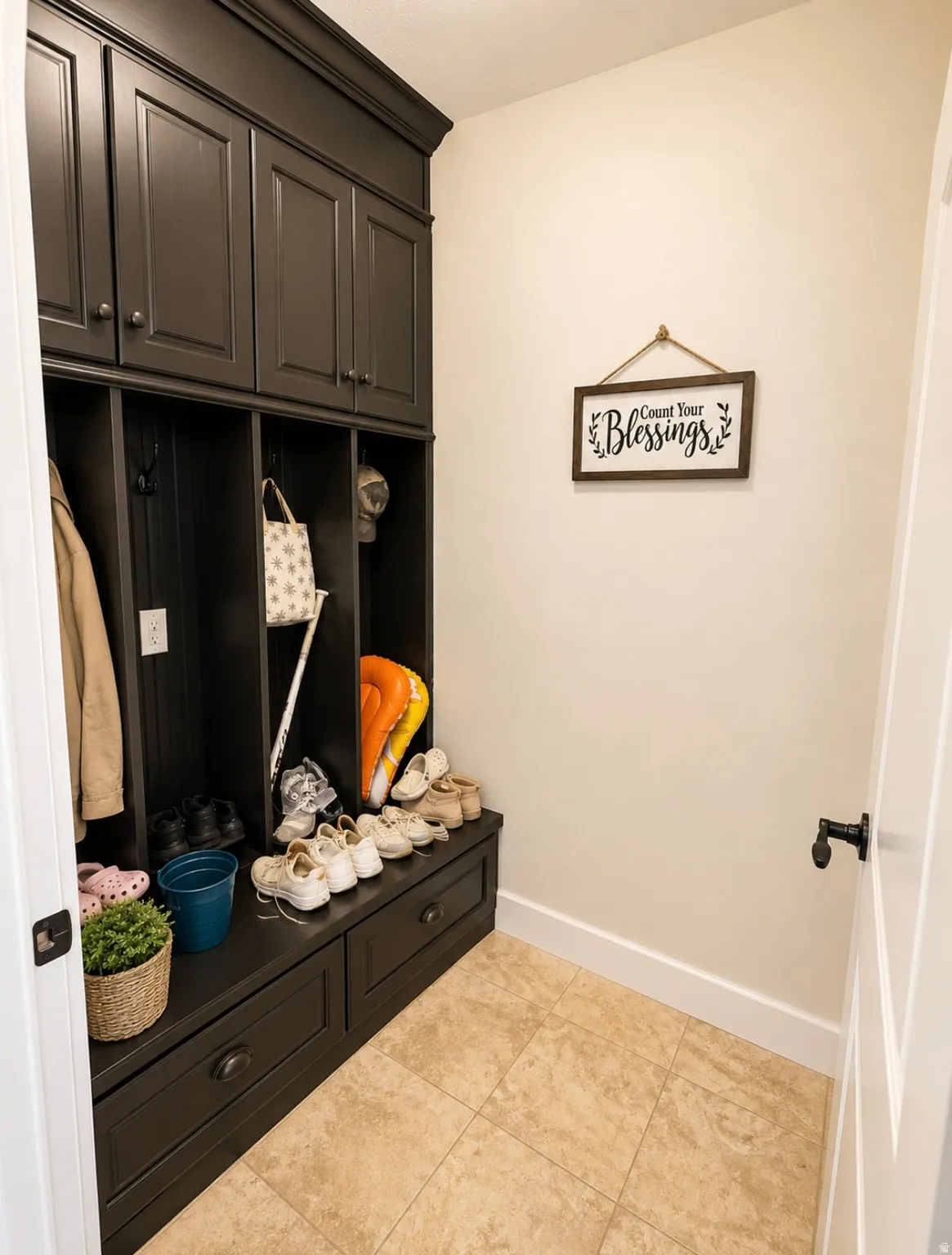 Built-in dark cabinetry featuring upper storage, open cubbies with hooks, and lower drawers
