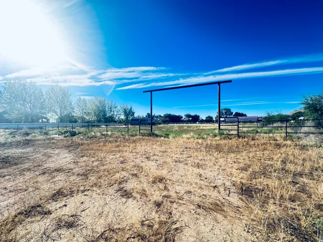 Expansive land parcel featuring a metal gate and perimeter fencing