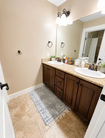 Double vanity with built-in cabinetry, dual white undermount sinks, and granite-look countertops