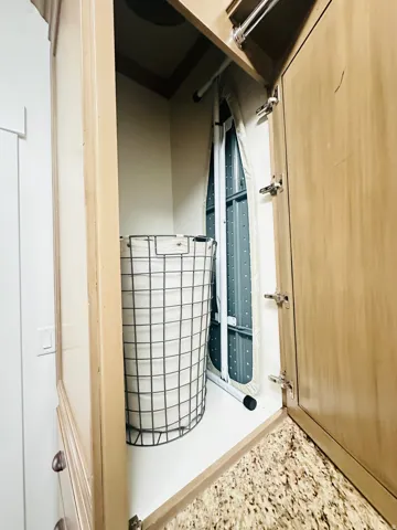 Built-in laundry shoot with a light wood-tone finish, granite-style countertop, and integrated storage space