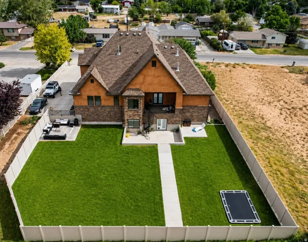 Expansive fenced backyard featuring a manicured lawn and a concrete patio space