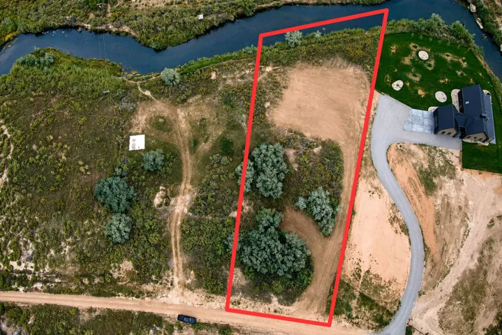 Expansive lot featuring a natural water boundary, a cleared building site, and varied natural vegetation