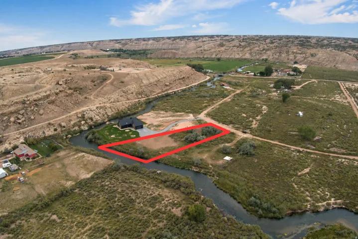 Riverfront land parcel featuring natural vegetation and surrounding open terrain