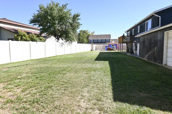 Expansive lawn featuring a white privacy fence, multi-level deck, and wood siding