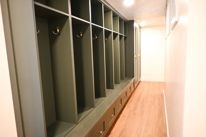 Built-in storage cabinetry with integrated hooks, multiple storage cubbies, lower drawers with brass-finish pulls, and wood-finish flooring
