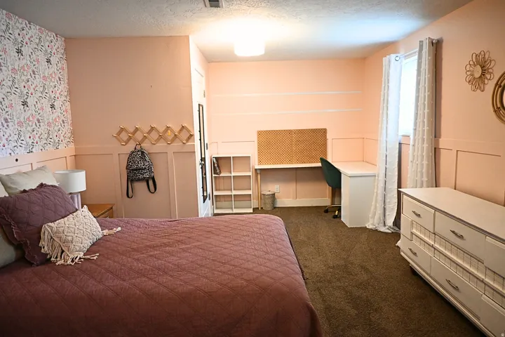 Built-in desk area with pegboard, wall-mounted accordion rack, and window with natural light