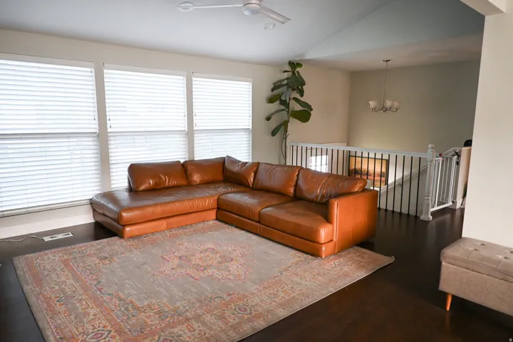 Vaulted ceilings, dark wood-finish flooring, white horizontal blinds, white railing with black spindles, and a ceiling fan