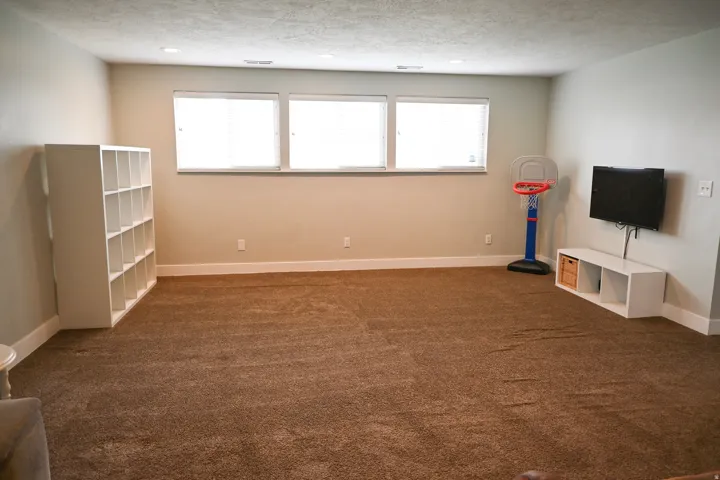 Spacious room featuring three windows with blinds, recessed lighting, and carpet flooring