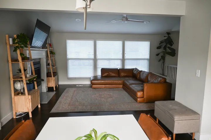 Expansive living area with dark wood-finish flooring, a contemporary ceiling fan, and a fireplace with a white mantel