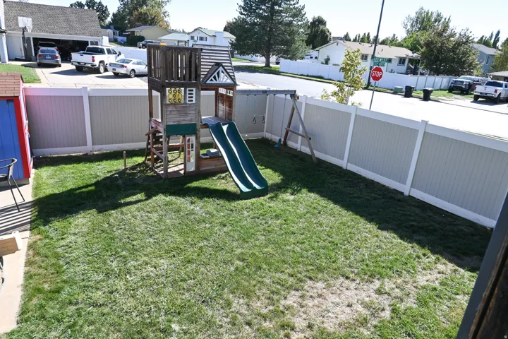 Fenced backyard with a wooden play structure and a storage shed