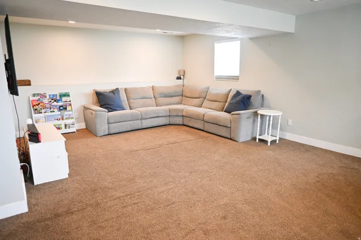 Recessed lighting, wall-mounted television bracket, neutral wall paint, window with blinds, and carpeted flooring