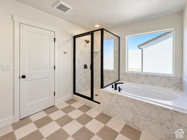 Freestanding bathtub with black fixtures, large window, and walk-in shower with black-framed glass enclosure