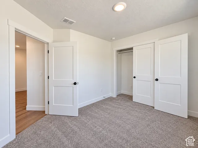 Neutral tone wall paint with recessed lighting, complemented by a textured carpet flooring