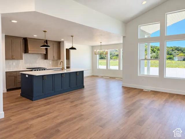 Spacious interior featuring a kitchen island with built-in storage, wood-finish flooring, ample natural light, and vaulted ceilings