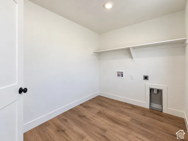Dedicated laundry area featuring wood-finish flooring, white walls, and a built-in storage shelf