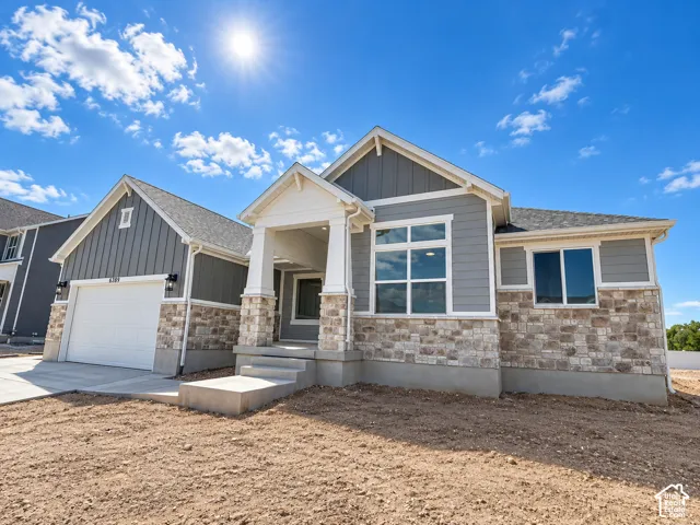 Craftsman-style home featuring a covered entry, stone and siding exterior, two-car garage, and clear-pane windows