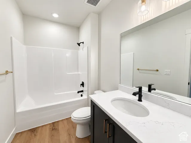 Wood-finish flooring with a white bathtub and black fixtures