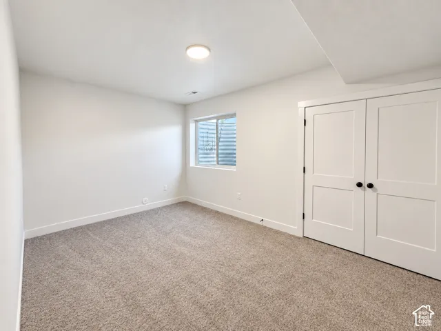 Neutral-toned carpeting, white walls, and a flush-mount ceiling light fixture