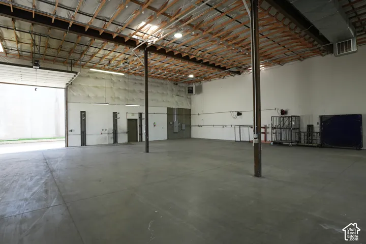 Expansive concrete flooring with high ceilings, exposed wood beam ceiling, and overhead lighting