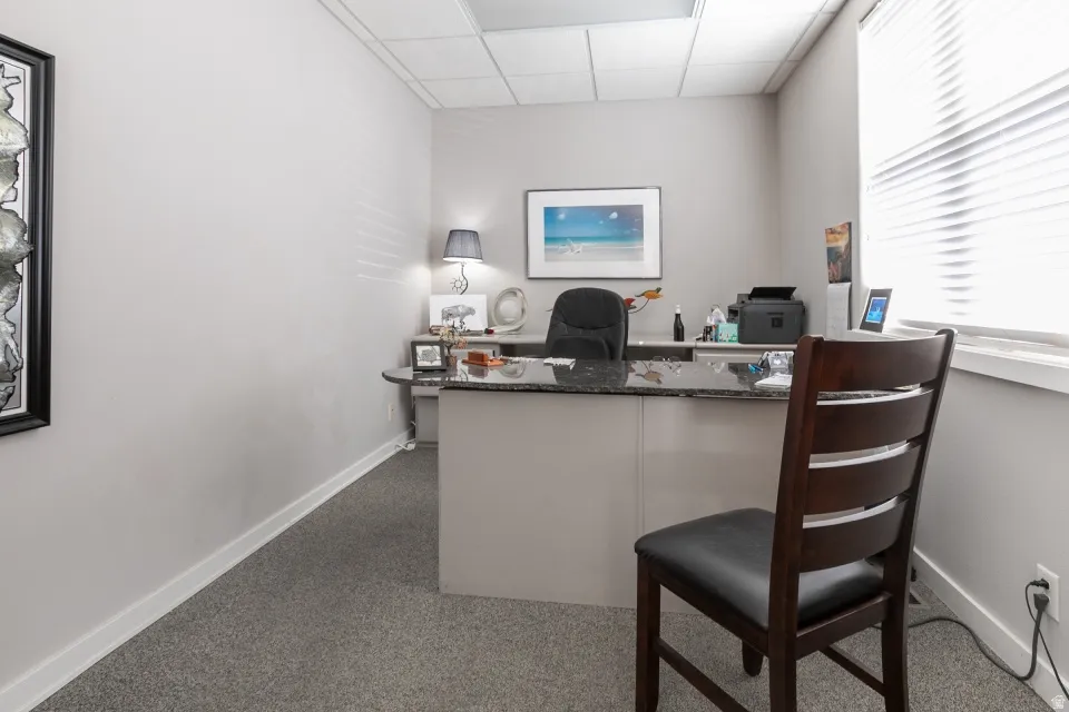 Recessed lighting, wall-to-wall carpeting, window blinds, built-in desk with a dark countertop, and perimeter baseboards