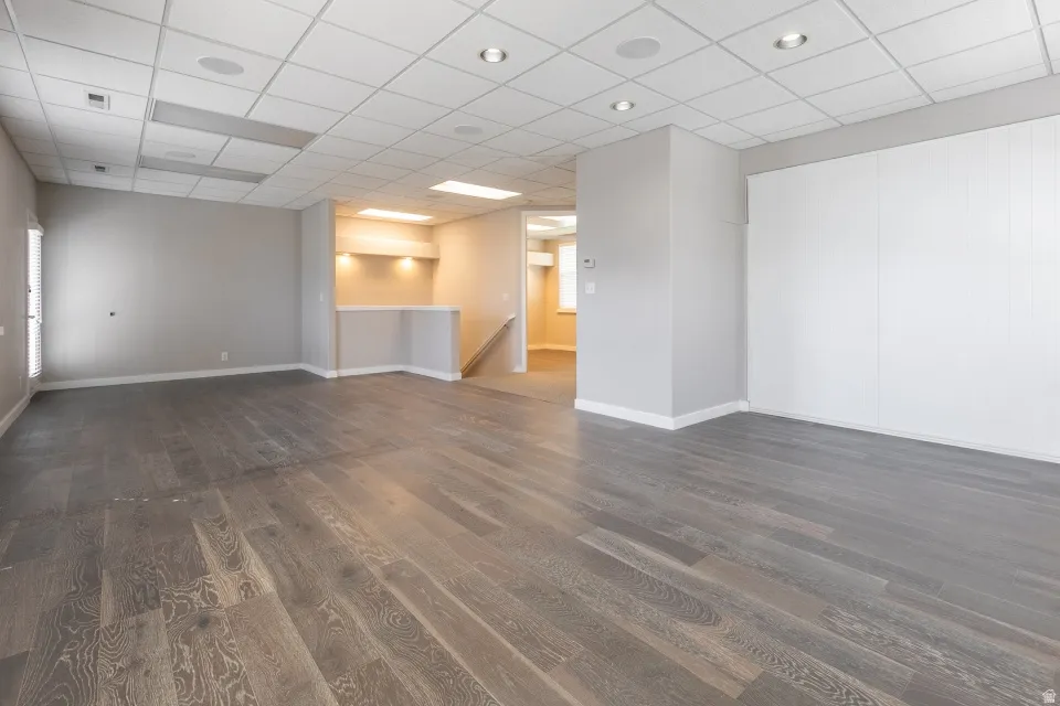 Spacious room featuring wood-finish flooring, recessed lighting, and a built-in bar area with integrated lighting