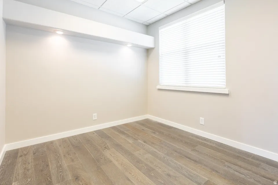 Wood-finish flooring, recessed lighting, neutral wall paint, and a window with blinds