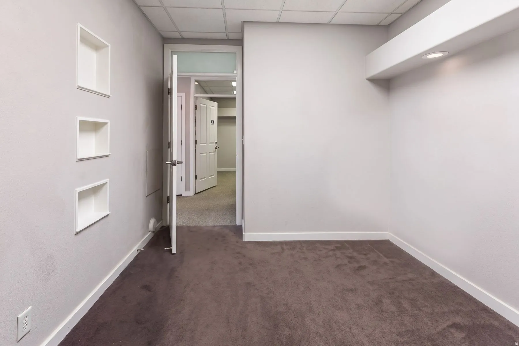 Built-in wall shelving, recessed lighting, drop ceiling, and neutral-toned carpeting
