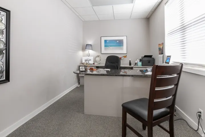 Recessed lighting, wall-to-wall carpeting, window blinds, built-in desk with a dark countertop, and perimeter baseboards