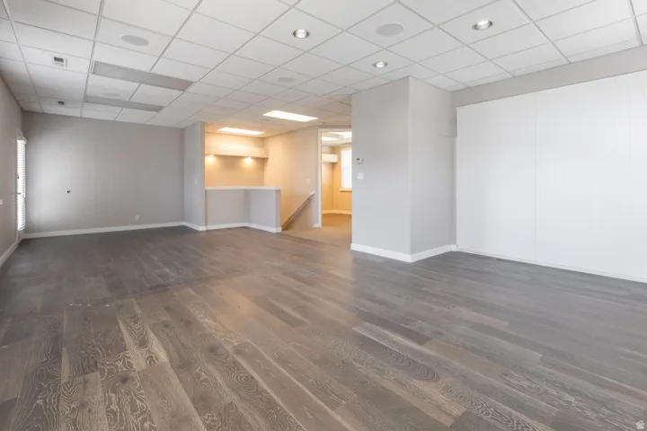 Spacious room featuring wood-finish flooring, recessed lighting, and a built-in bar area with integrated lighting