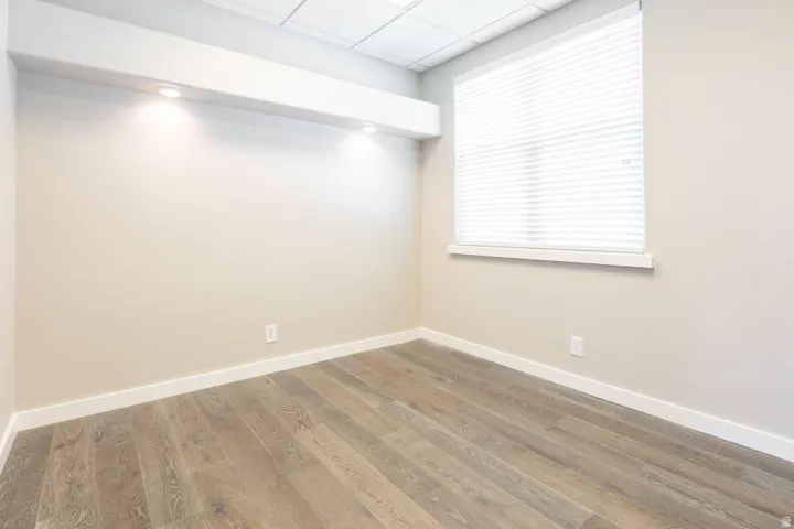 Wood-finish flooring, recessed lighting, neutral wall paint, and a window with blinds
