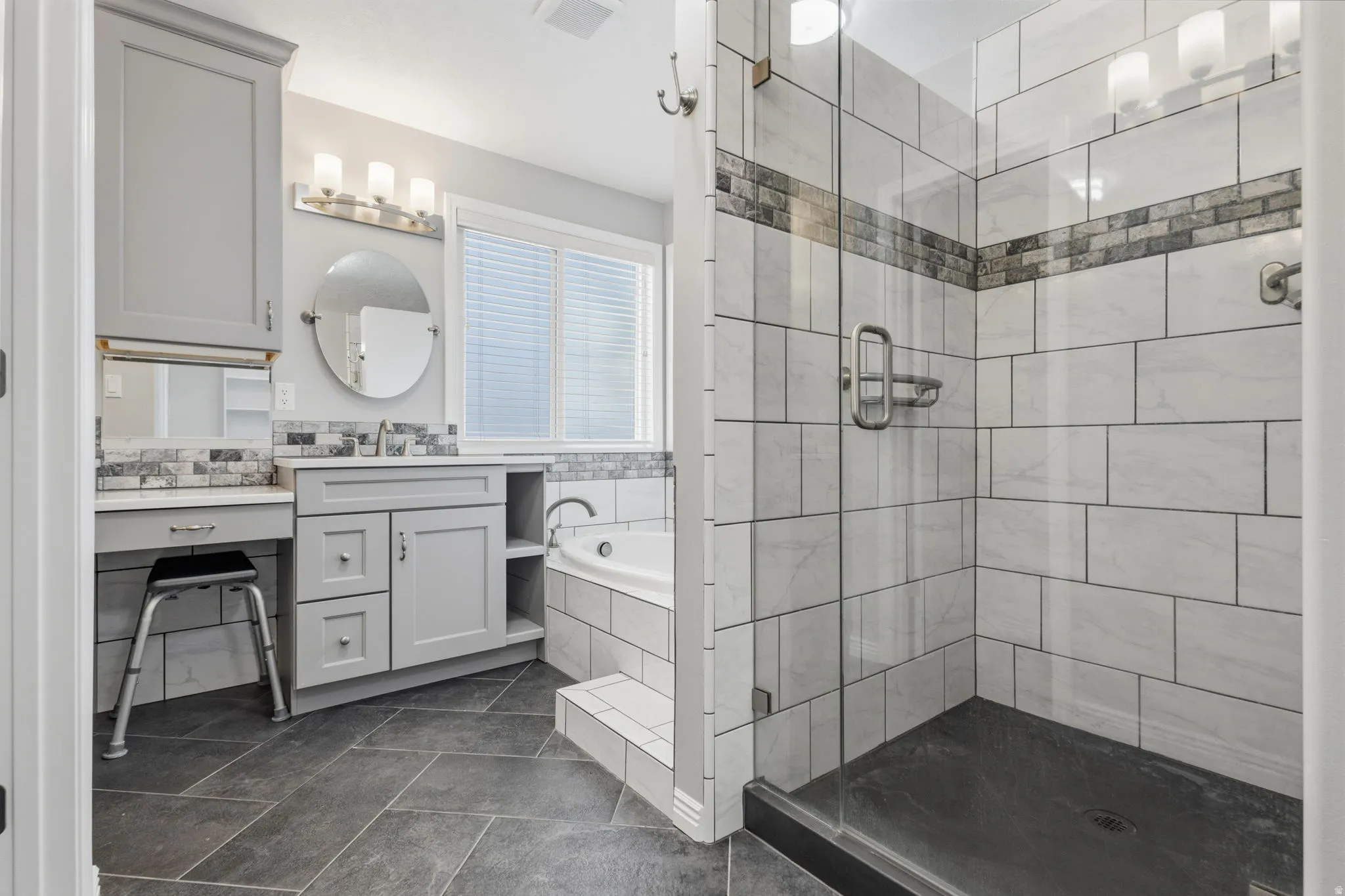 Modern walk-in shower with glass enclosure, subway tile surround, and decorative tile accent band