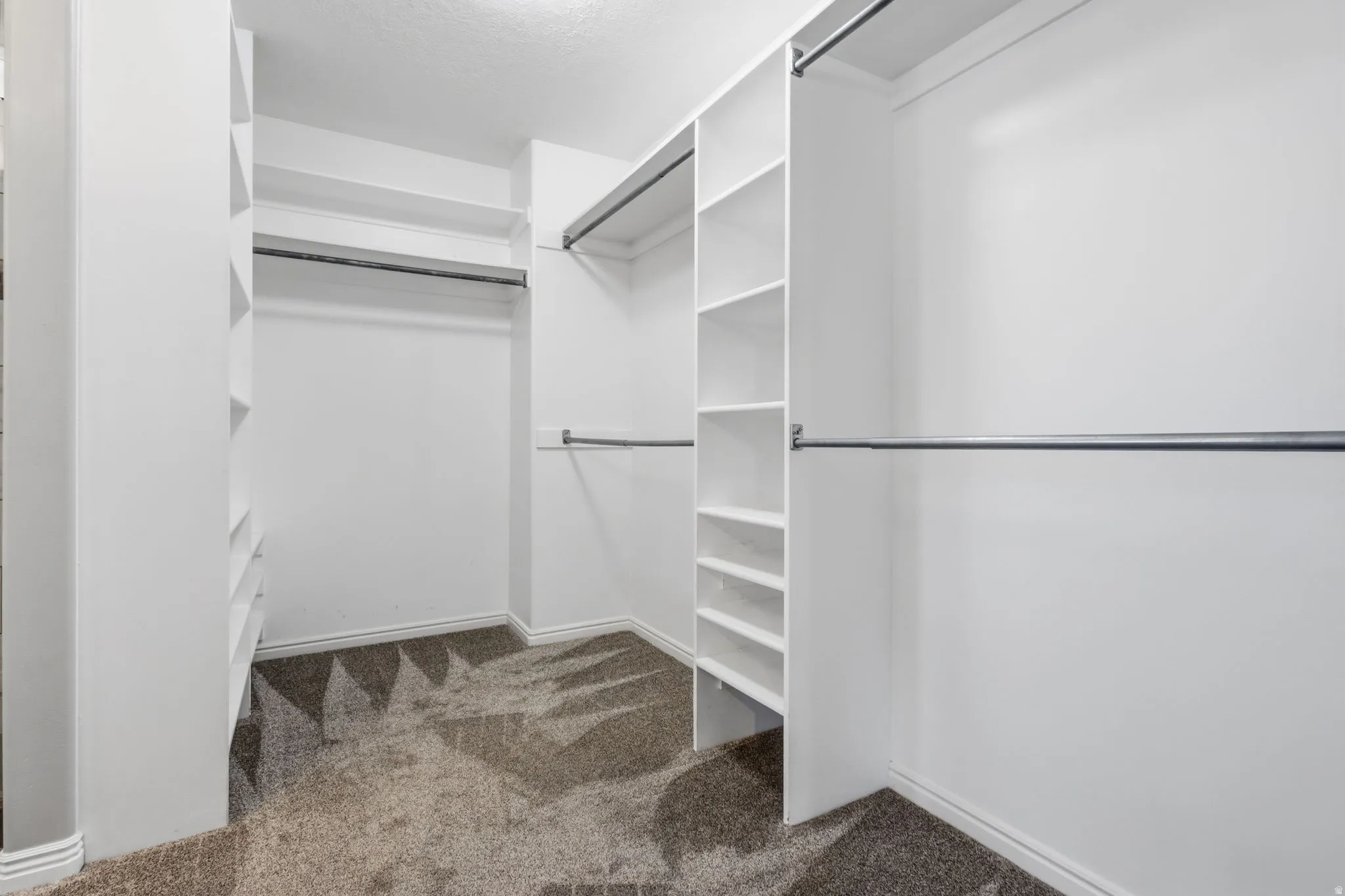 Built-in shelving, multiple hanging rods, and patterned carpeting