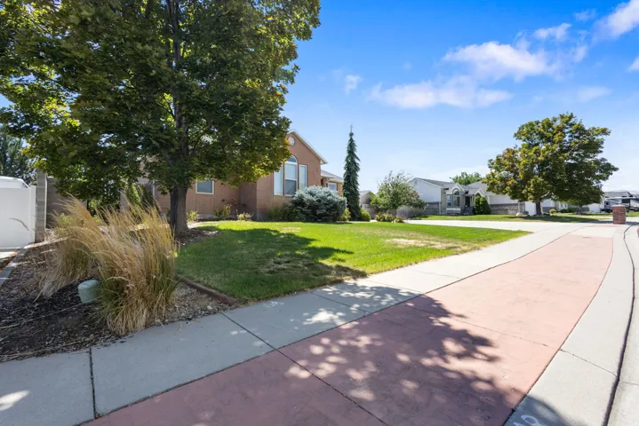 Brick exterior with arched window, concrete and paver sidewalk, mature trees, and established landscaping