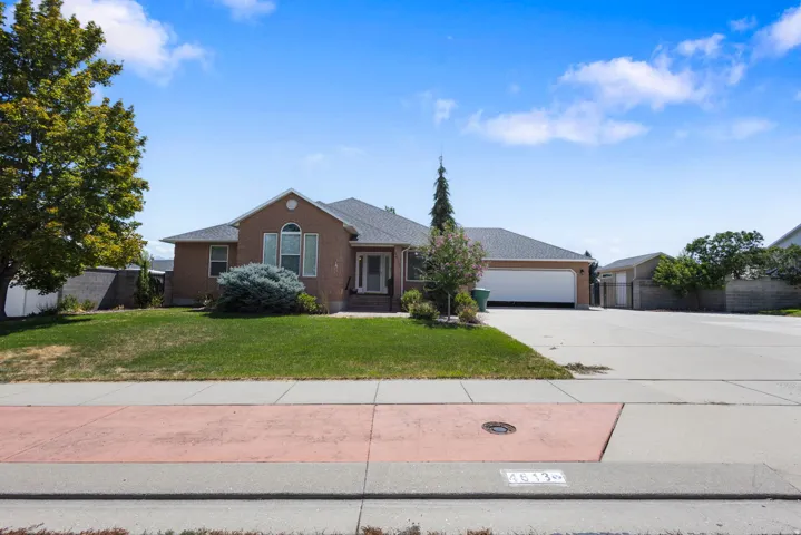 Brick exterior residence with an attached garage, arched window, and mature landscaping