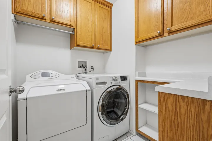 Wood-finish cabinetry with silver hardware, white countertops, built-in shelving, and a metal hanging rod