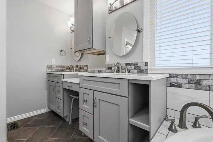 Dual vanity with gray cabinetry, white countertops, and brushed nickel fixtures