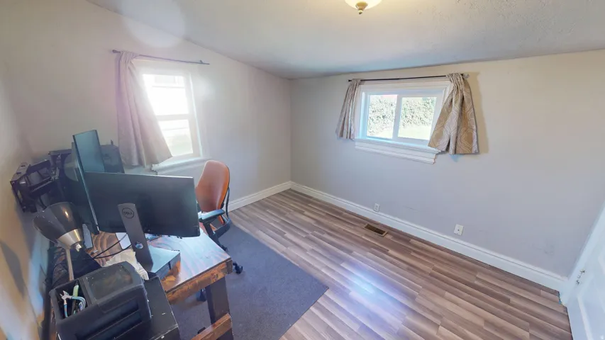 Room featuring two windows, wood-finish flooring, and light-toned wall paint