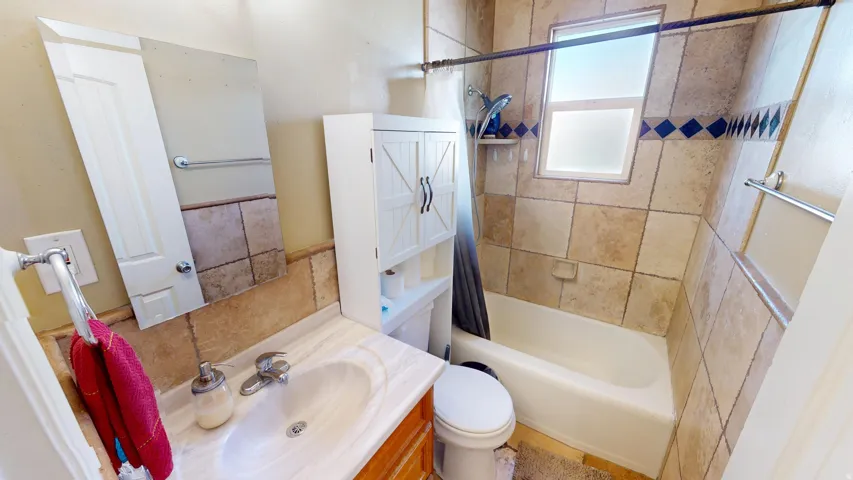 Warm-toned tile surround with decorative accent band, built-in bathtub, and a window