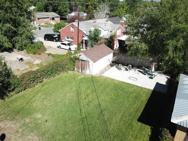 Expansive green lawn, concrete patio, mature trees, detached storage shed