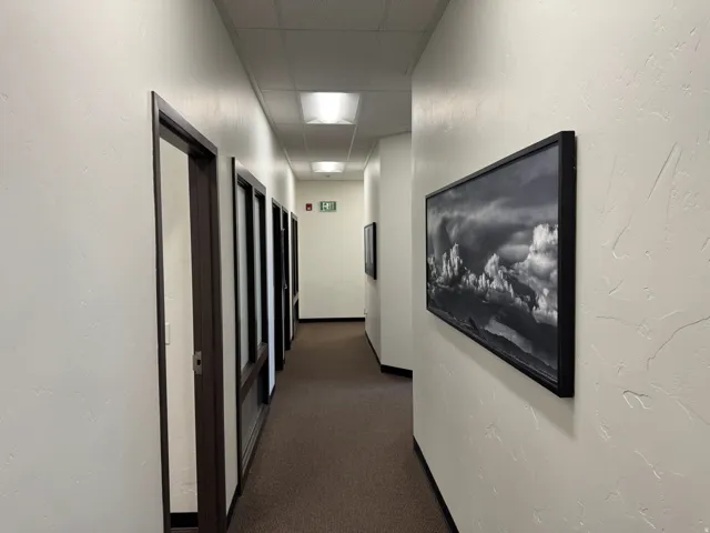 Hallway with recessed lighting, textured walls, and brown-framed doors featuring glass panels