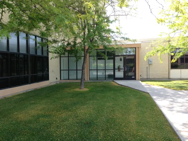 Brick exterior with extensive black-framed windows, a prominent glass entry, and a concrete pathway