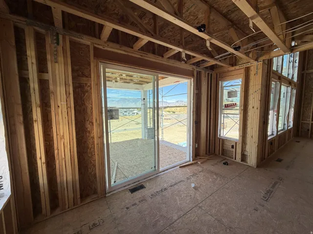 Sliding glass door to an outdoor area, multiple windows, exposed wood framing, and plywood subflooring